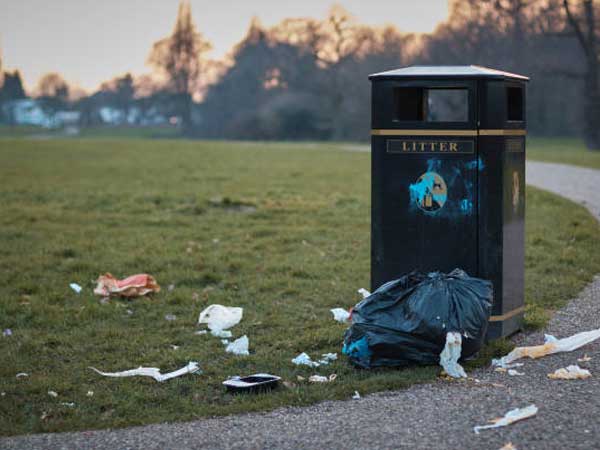 Litter beside a garbage can along park pathway
