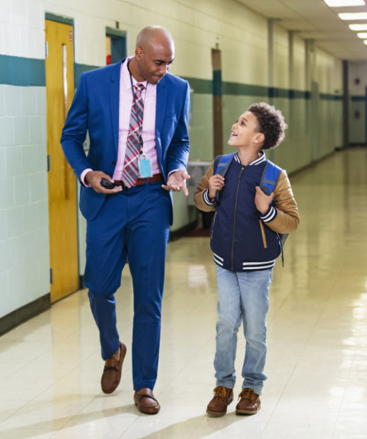 Image of a teacher and student walking together and smiling in a school hallway